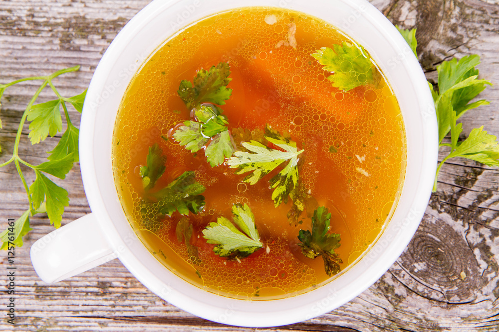 Chicken soup with carrots and parsley on wooden background Chicken soup with carrots and parsley on wooden background