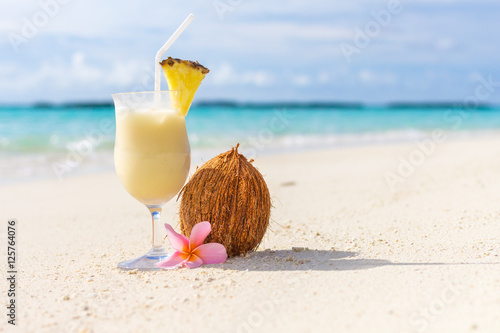 Pina Colada cocktail on the beach with coconut and exotic flower photo