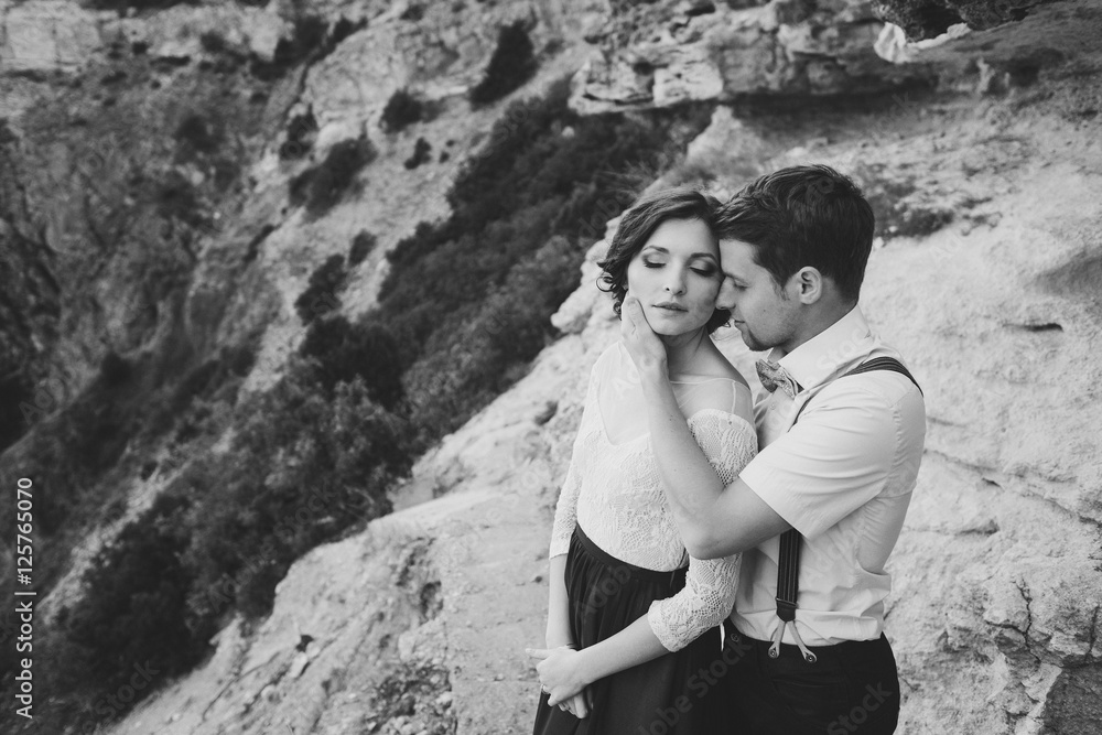 Romantic and stylish caucasian couple hugging on the background of spectacular view. Love, relationships, romance, happiness concept. Black and white image.