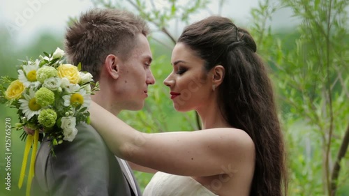Newlyweds kissing on the background of nature photo