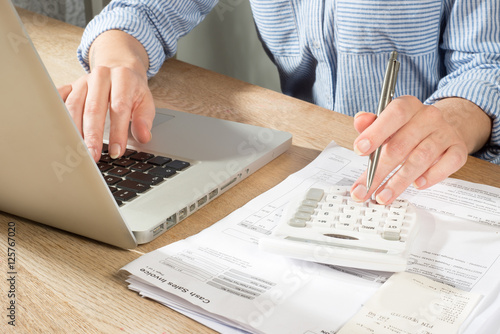Hands Using Calculator and Laptop to Complete Accounts