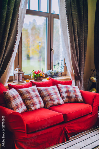 Daybed with cushions in rustic home. on the table bouquet of flowers and a candlestick pumpkin