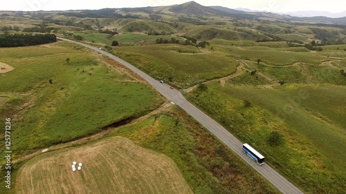 秋の阿蘇山 外輪山道路と広がる牧草地にトラクターや干し草ロールがある風景