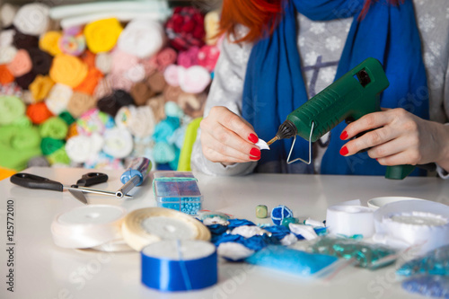 Woman glues glue gun. Woman doing kanzashi of satin ribbons. Wom photo