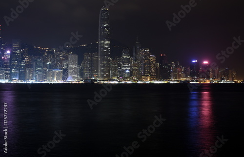 Beautiful night view of Hong Kong island skyline across Victoria Harbour from Avenue of Stars at Kowloon. Skyscrapers on waterfront in downtown. Global financial center.
