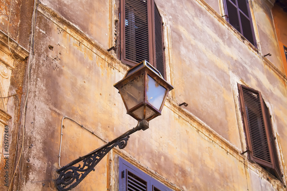 View of old, traditional street lamp on historical building in Trastevere area of Rome
