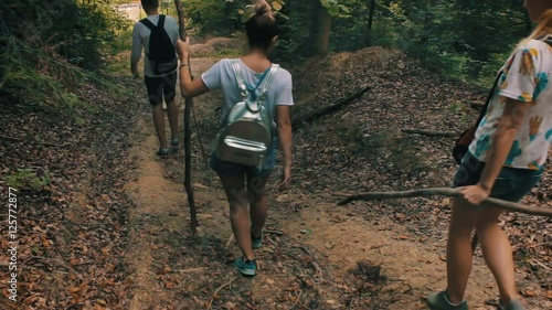 A group of tourists out of the woods, walking along the forest path.