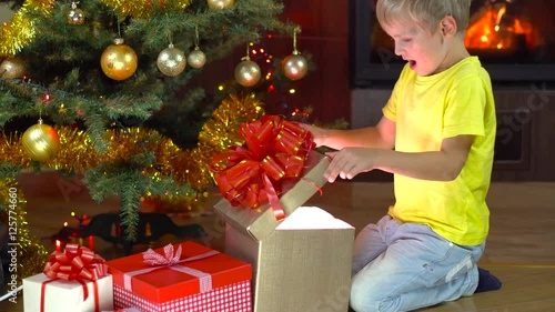 cute boy open his present at christmas tree