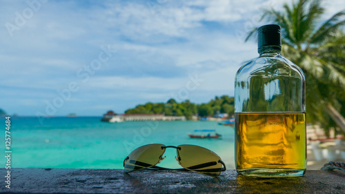 Fotografia Beach party. Holiday fun concept. Bottle of rum and sunglasses w