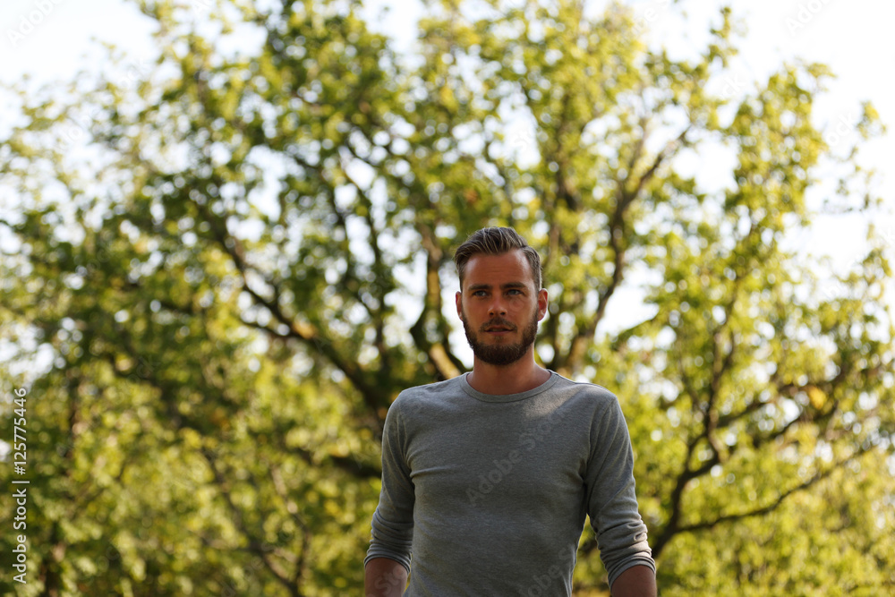 A lonely handsome man wearing a grey shirt and jeans, walking up on a hill on a sunny summer day. A lonely handsome man wearing a grey shirt and jeans, walking up on a hill on a sunny summer day.