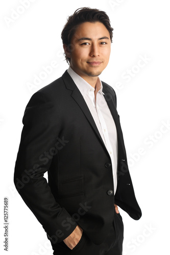 An attractive businessman wearing a black blazer with a white shirt, standing against a white background looking at camera. Smile on his face.