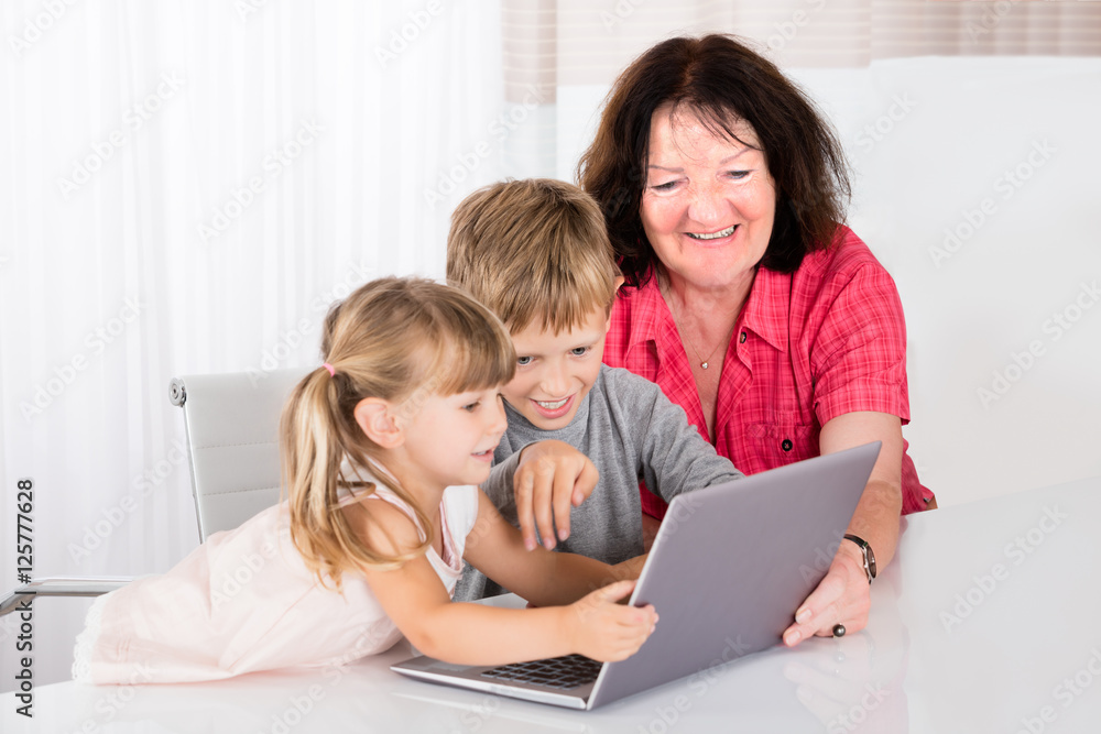 Happy Grandmother With Her Grandchildren Using Laptop Happy Grandmother With Her Grandchildren Using Laptop