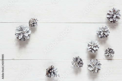 Snow painted pine cones on rustic white wood table. Space for te