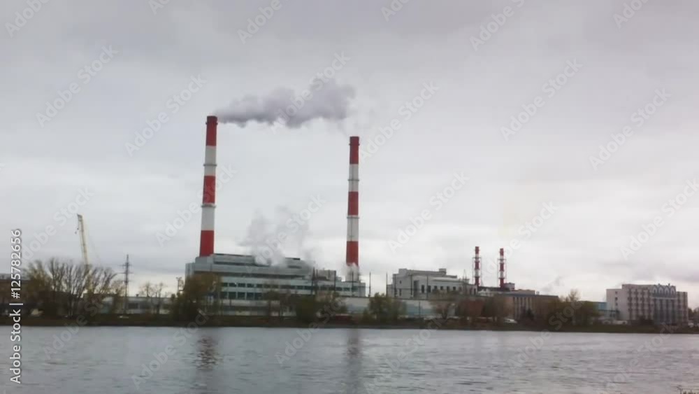 Industrial landscape - thermal power plant over the river, smoke from tube Industrial landscape - thermal power plant over the river, smoke from tube