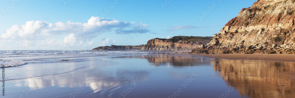 Mountain reflected in the smooth water of the beach Areia Branca. Lourinha, West coast of Portugal