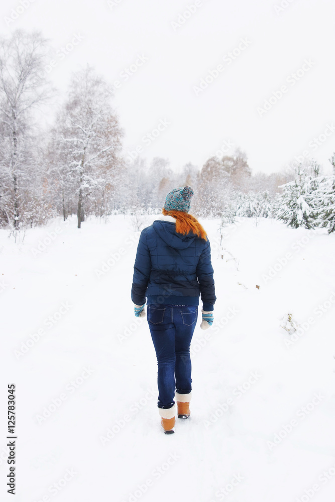 Slim young woman walking in a winter park