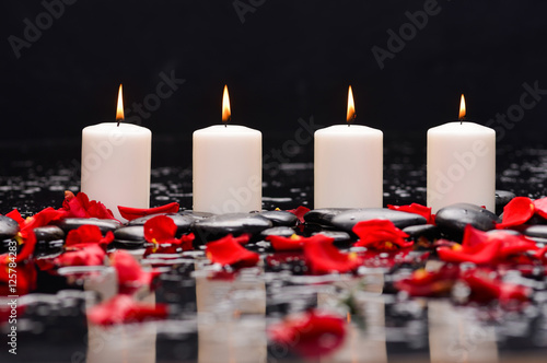 Still life with many rose petals with three candle and therapy stones 