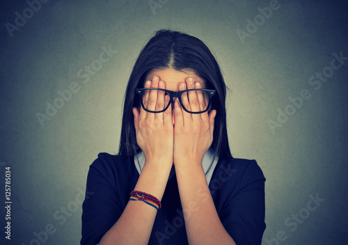 woman in glasses covering face eyes using her both hands