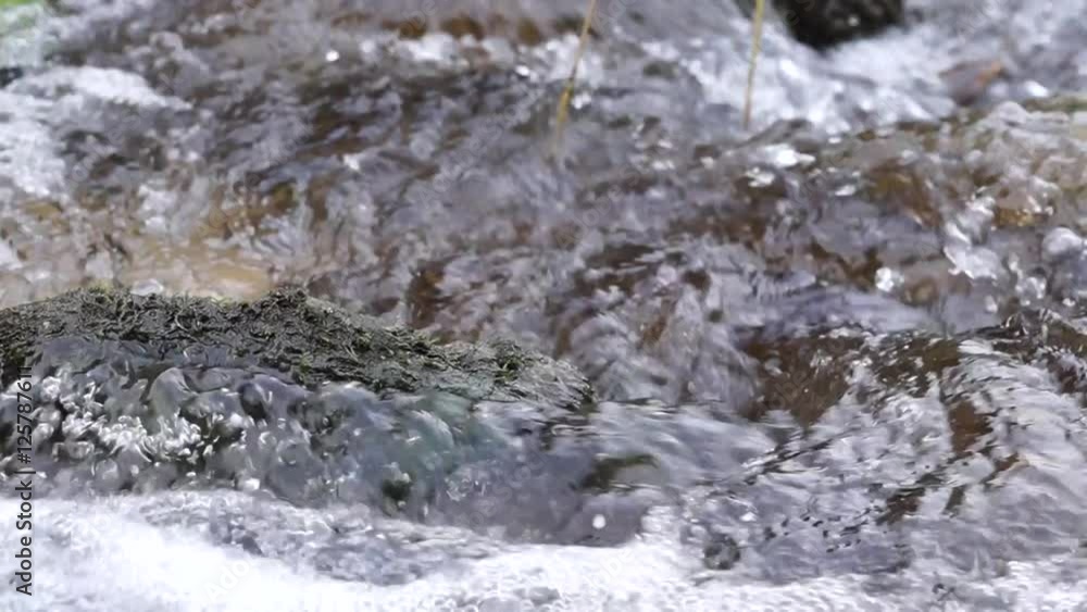 Stein mit Moos ragt aus Fluss Stein mit Moos ragt aus Fluss