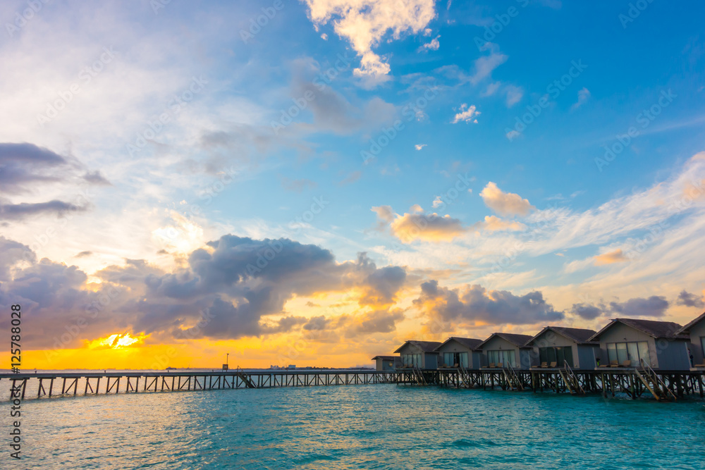 Obraz premium Beautiful sunrise with water villas in tropical Maldives islan