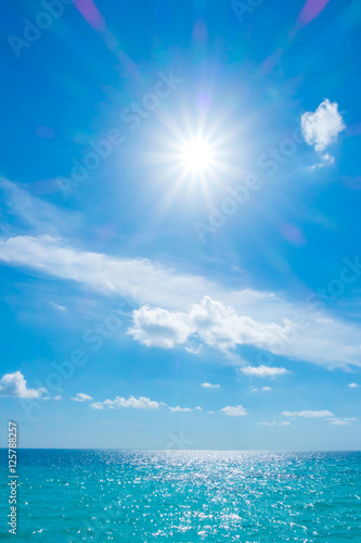 White clouds with blue sky and sun over calm sea in tropical Ma