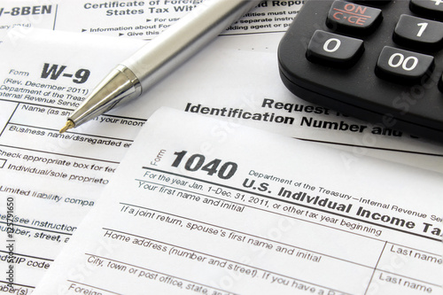 US tax form with pen and calculator, over light [blur and select focus background]