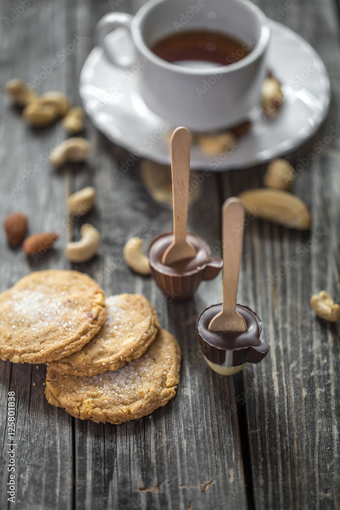 chocolates with tea and nuts on wooden background chocolates with tea and nuts on wooden background