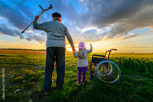 Vászonkép Miracle recovery: Old man gets up from wheelchair and raises hands up
