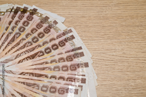 Thousand bath Thai money on wooden table with copy space