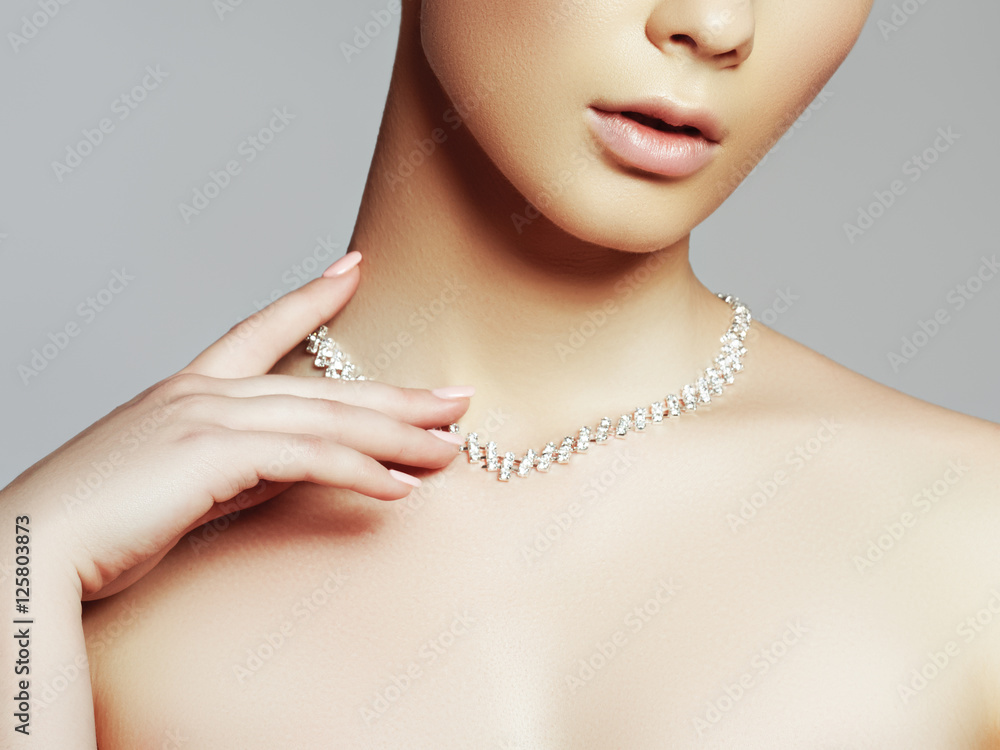 Elegant fashionable woman with jewelry. Beautiful woman with a diamond necklace. Beauty young model with a diamond pendant on a gray background. Jewellery and accessories. Beauty and fashion concept