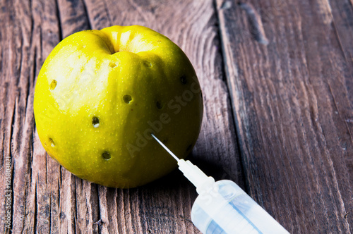 Green apple being injected with a syringe