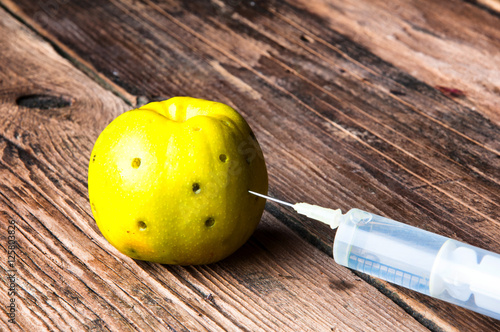 Green apple being injected with a syringe