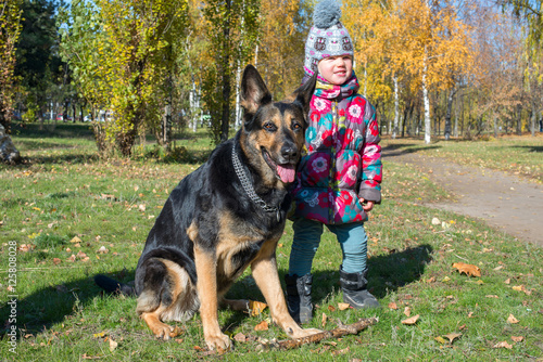 Funny little girl with big dog are resting in park