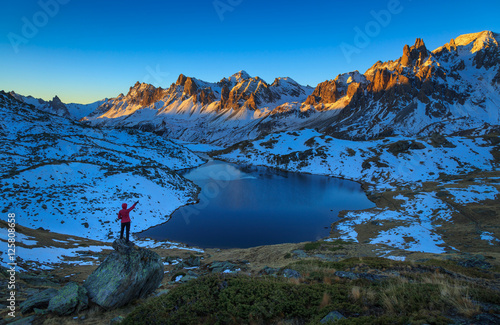 Woman pointing toward the mountians during a clear, autumn sunrise in the Claree valley in France.