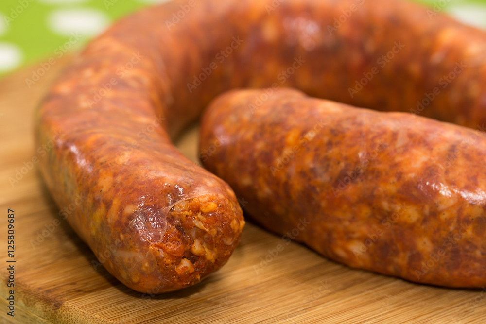 Fototapeta premium Closeup macro domestic red sausage on the wooden board