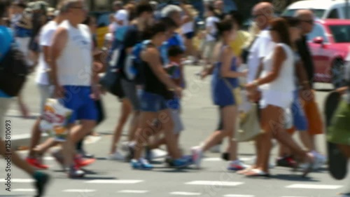 Side view blurred pedestrians crossing a street in the city of Barcelona in summer.