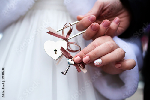Bride and groom with decorated padlock of love with keys