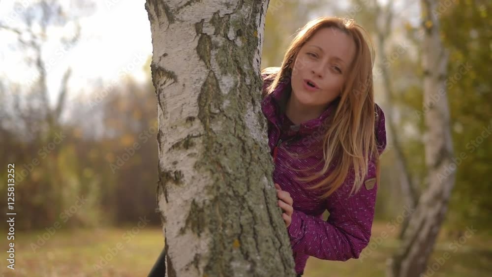 Mother and young son are hiding behind a tree and play,outdoors in autumn Mother and young son are hiding behind a tree and play,outdoors in autumn