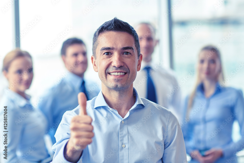 smiling business team showing thumbs up in office smiling business team showing thumbs up in office