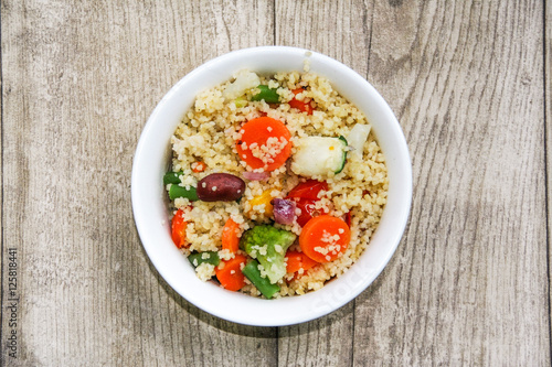bowl of vegetarian cous cous isolated on a wooden background  photo