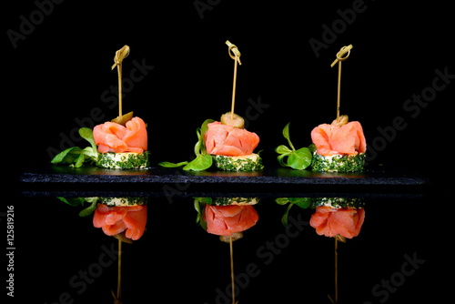 canapes with salmon and capers on black background photo