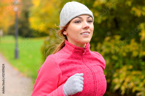 Smiling fit young woman jogging in a park