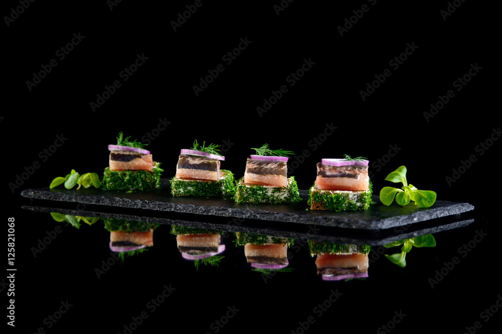 Canapes of herring with bread and cream cheese on black backgrou Canapes of herring with bread and cream cheese on black backgrou