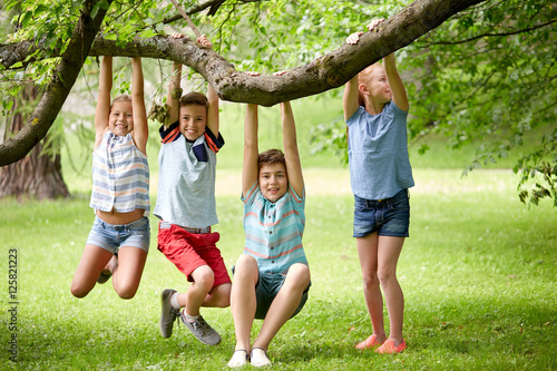 happy kids hanging on tree in summer park