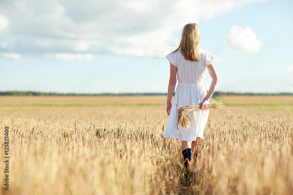 young woman with cereal spikelets walking on field young woman with cereal spikelets walking on field