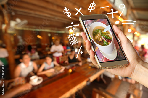 Woman Hand holding smartphone with Geometry symbol in the restaurant for order some food