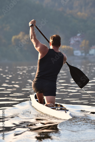Canoe sportsman rowing in a lake. Athletic water sport. photo