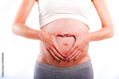 Pregnant Woman holding her hands in a heart shape on her baby bu