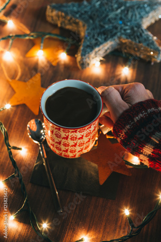 Hands holding a cup of hot chocolate with Christmas lights photo