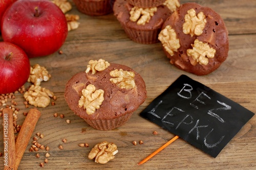 Gluten free muffins from buckwheat flour, apple, cinnamonand walnuts on brown wooden background with index card with text no gluten in czech language